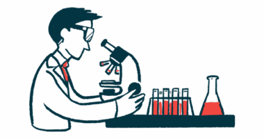 A person in a white coat looks into a microscope, with a beaker and rack containing half-filled vials nearby.