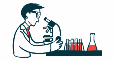 A person in a white coat looks into a microscope.